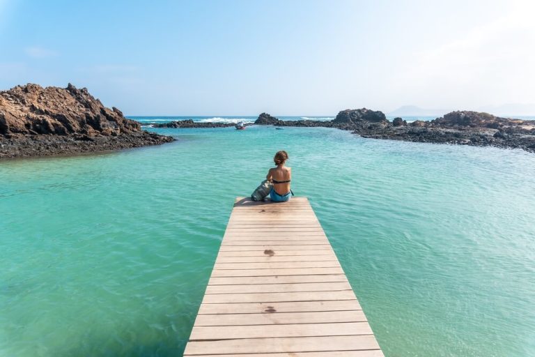 A young woman lying on the wooden walkway on Isla de Lobos, off the north coast of the island of Fuerteventura, Canary Islands. Spain